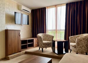 ロゼネッツにあるFamily Hotel Kontesaの椅子2脚とテレビが備わるホテルルームです。