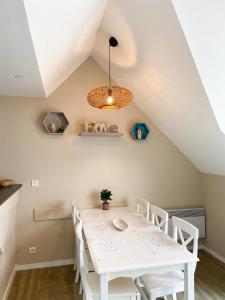 - une salle à manger blanche avec une table et des chaises blanches dans l'établissement Appartement en duplex front de mer, Cap Coz, à Fouesnant