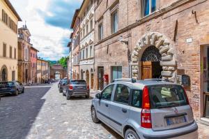 um carro estacionado numa rua ao lado de um edifício em Appartamento Valbona nel cuore di Urbino em Urbino