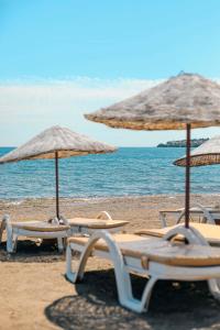 a group of lounge chairs and umbrellas on a beach at MALİBEACH APART OTEL in Seferihisar