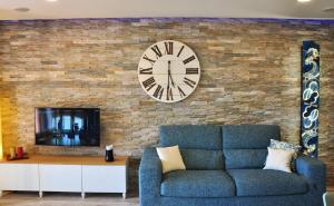 a living room with a couch and a clock on a brick wall at Una spettacolare vista mare - Casa con Jacuzzi in Bergeggi