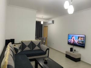 Redona Apartament في فلوره: غرفة معيشة مع أريكة وتلفزيون على الحائط