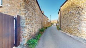 eine Gasse mit einer Ziegelwand und einem Holztor in der Unterkunft Hannah Cottage in Adderbury