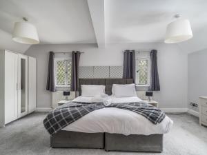 a bedroom with a large bed and two windows at Pass the Keys Prestigious 5 Bed Retreat Spacious Tranquil Haven in Radlett