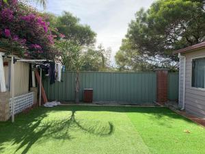 einen Hinterhof mit einem Zaun und einem Garten mit grünem Gras in der Unterkunft Nice house in canning vale in Perth