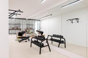dwóch mężczyzn ćwiczących w siłowni z lustrami w obiekcie The Olive Boutique Suites & Spa w mieście Cala Llonga