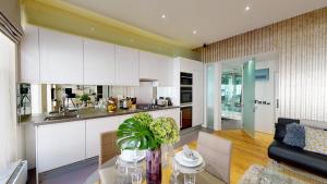 a kitchen with white cabinets and a glass table at The Harrington - Gloucester Road - 3 Harrington Gardens in London