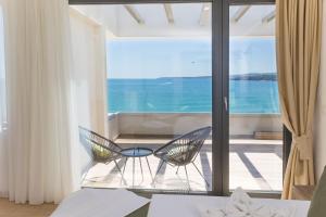 a bedroom with a view of the ocean with two chairs at Olive Villas Beach Hotel in Sozopol
