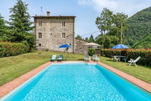 a pool in front of a building with chairs and umbrellas at Casa Paola in Pescaglia