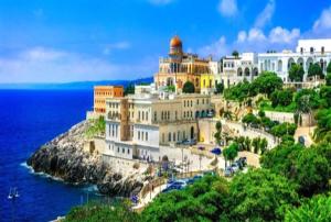 ein großes Gebäude auf einem Hügel neben dem Meer in der Unterkunft Residence Ginevra-Porto Miggiano in Santa Cesarea Terme