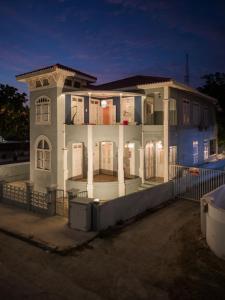 een groot wit huis met zuilen en een hek bij Villa Amalie & Villa Curiel in Willemstad