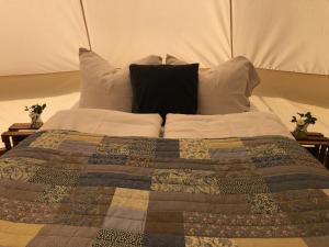 a bed with a quilt and pillows on it at Helles Have Glamping in Stege