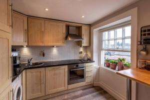a kitchen with wooden cabinets and a sink and a window at Royal View Apartments in Kirkby Lonsdale