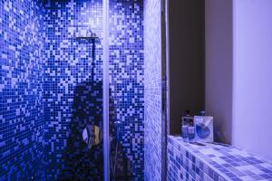 a bathroom with a shower with blue tiles on the wall at Serendipity Rooms in Milan