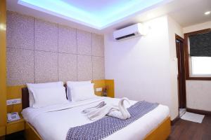 um quarto com uma cama com toalhas brancas em Hotel Emirates em Calcutá