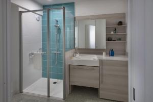 La salle de bains est pourvue d'une douche, d'un lavabo et d'un miroir. dans l'établissement Résidence DOMITYS CHATEAU CAMAS, à Pin-Balma