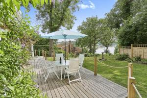 a wooden deck with a table and an umbrella at Kipper Cottage in Wootton Bridge