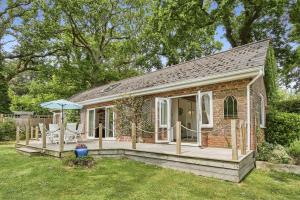 een klein bakstenen huis met een veranda en een paraplu bij Kipper Cottage in Wootton Bridge