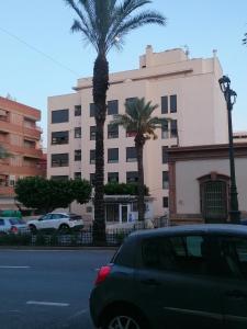 un coche aparcado frente a un edificio con palmeras en Apartamento Moya - Playa y Sol, en Aguadulce