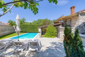 basen z 2 leżakami i parasolem w obiekcie Holiday House Mlin w mieście Kras