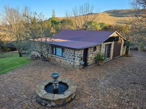 ein Steinhaus mit einem Brunnen davor in der Unterkunft Stone Cottage in Dullstroom
