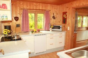 una cocina con armarios blancos y cortinas rosas en Ferienhaus Talblick en Weiler-Simmerberg