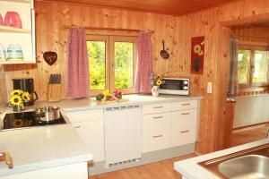 una cocina con armarios blancos y cortinas rosas en Ferienhaus Talblick, en Weiler-Simmerberg