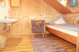1 dormitorio con 1 cama, lavamanos y silla en Ferienhaus Talblick en Weiler-Simmerberg