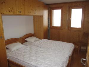 een bed in een houten kamer met 2 ramen bij Residenz Plein Ciel, Wohnung MARMOTTE VEYS210 in Veysonnaz