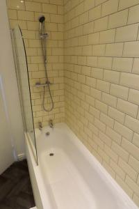 a white bath tub with a shower in a bathroom at The King Stay in Manchester