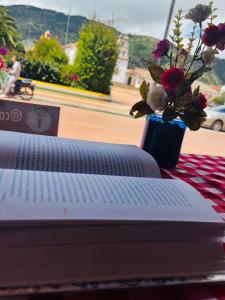 a book sitting on a table with a vase of flowers at Camino A La Villa Cucaita Hotel in Cucaita