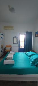 uma grande cama verde num quarto com uma janela em Milisia Rooms em Samothráki
