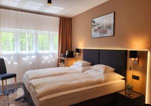 um quarto de hotel com duas camas e uma cadeira em Villa Bauhaus Wellness Apart-Hotel em Siófok