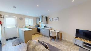 a living room with a kitchen and a tv at Texel Barn in Witney