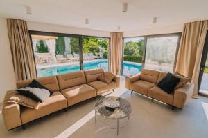 ein Wohnzimmer mit einem Sofa, einem Tisch und einem Pool in der Unterkunft CROWONDER Santa Barbara Majestic Villa with Large Heated Swimming Pool and Sauna in Privlaka