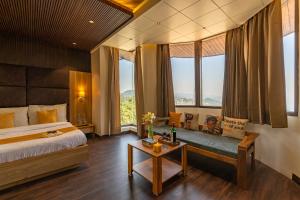 a bedroom with a bed and a table and windows at ArtBuzz Mussoorie in Mussoorie