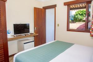 sypialnia z łóżkiem, telewizorem i oknem w obiekcie O Tempo e o Vento w mieście Natal