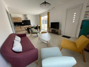 ein Wohnzimmer mit einem lila Sofa und Stühlen in der Unterkunft Val des Bruyères - gîte 15mn Pézenas avec terrasse et cour close - Parking privatif securisé - Wifi gratuit in Néffiès