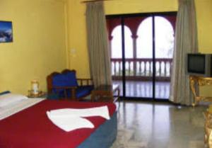 a bedroom with a bed and a balcony with a television at Shiv Sagar Palace,Ganpatipule in Ganpatipule