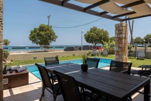 a patio with a table and chairs and a swimming pool at Villa Per Mare in Maleme