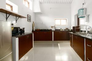 a large kitchen with brown cabinets and a white floor at Laika Heritage Stay in Mysore