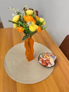 eine Vase mit Blumen und ein Teller mit Essen auf dem Tisch in der Unterkunft Daniela's rooms in Hunedoara