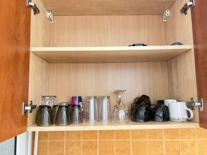 a shelf in a cupboard with various utensils at Daniela's rooms in Hunedoara