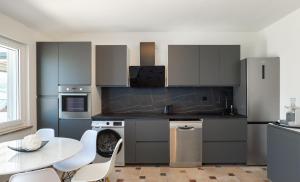 a kitchen with gray cabinets and a table with chairs at Pool apartment Ena in Pag