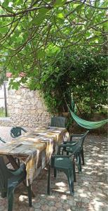 une table, des chaises et un hamac sous un arbre dans l'établissement Holiday Home Family - 100m from sea, à Vantačići