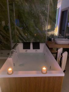 a bath tub with two candles in a bathroom at Alma Salina Suite in Margherita di Savoia