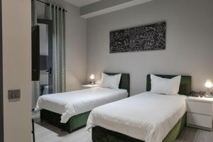 2 camas en una habitación de hotel con sábanas blancas en Sapiens Hotel en Tashkent