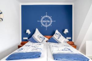 um quarto com uma parede azul e 2 camas em Inselhotel Arfsten em Wyk auf Föhr