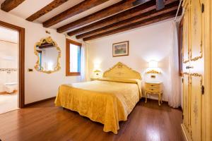 ein Schlafzimmer mit einem Bett mit gelber Tagesdecke in der Unterkunft Ca' Pinelli in Venedig
