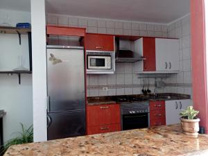 a kitchen with red cabinets and a stainless steel refrigerator at Sol y terraza in Playa Honda